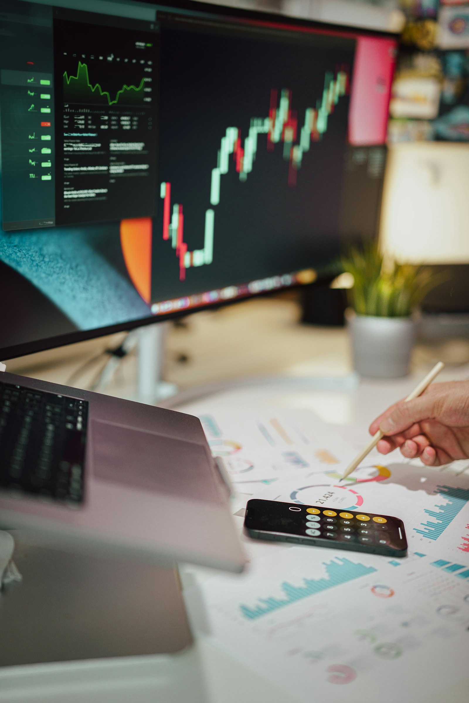 Persona analizando información financiera junto a un monitor con gráficos
