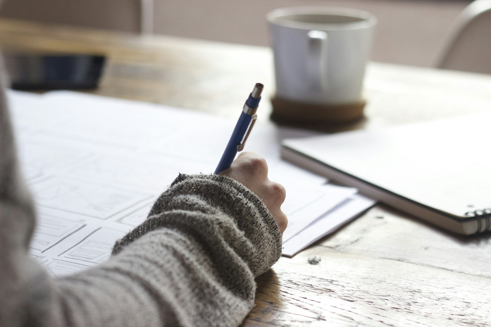 Persona escribiendo sus objetivos en un cuaderno sobre una mesa de madera